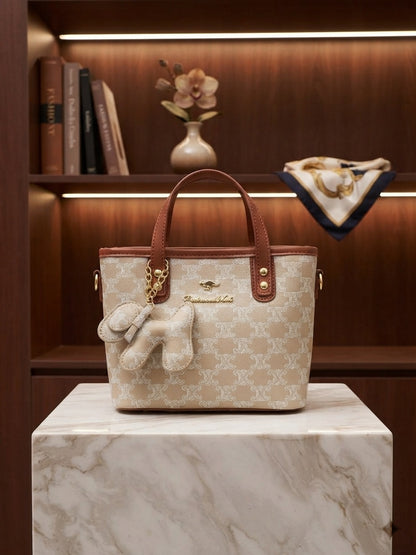 Beige monogram print structured tote bag with tan handles and animal charm