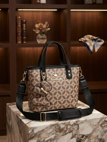 Structured tote bag with geometric monogram pattern, black crossbody strap, animal charm