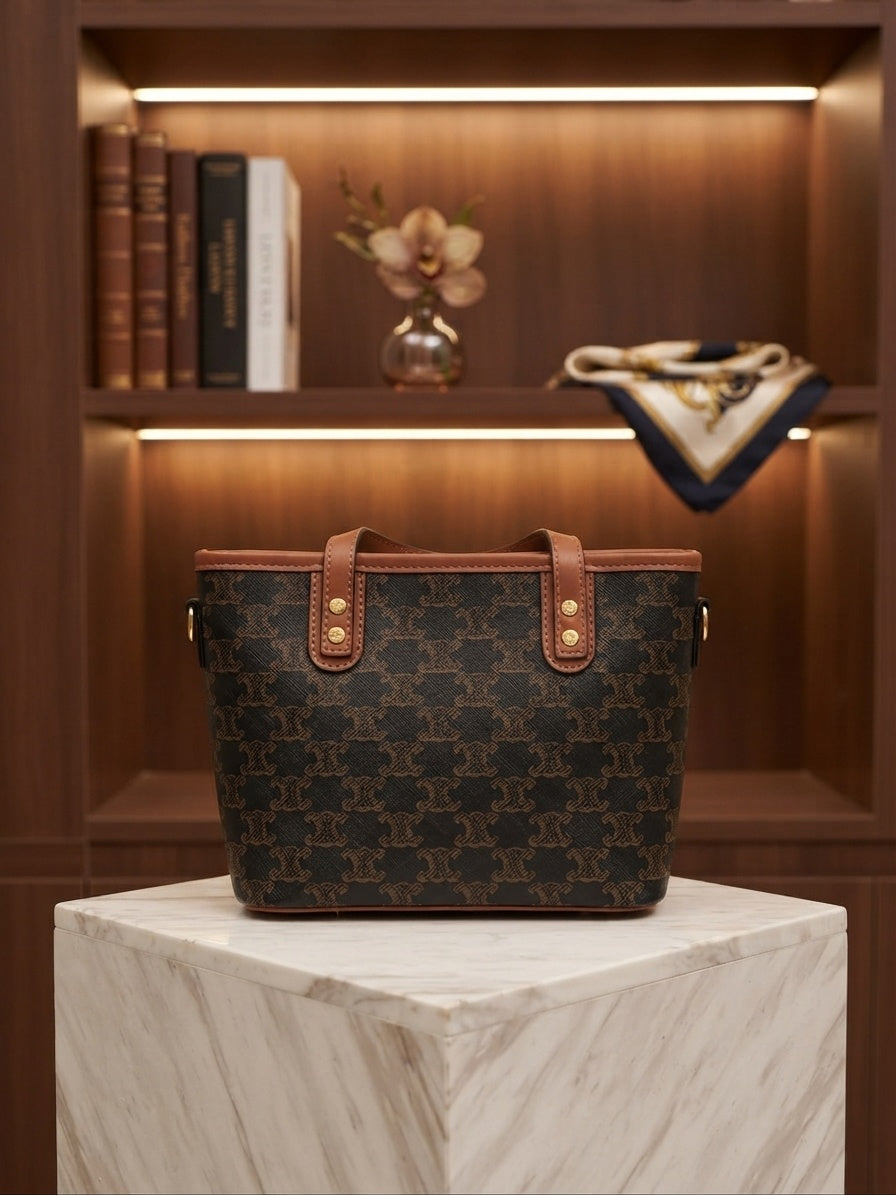 Structured tote bag with dark monogram print, tan leather handles, animal charm