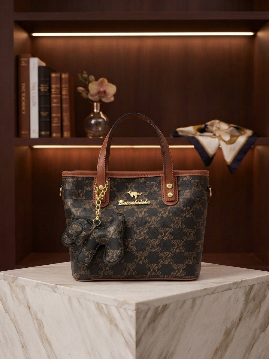 Dark monogram tote bag with tan trim, top handles, hanging animal charm and clasp