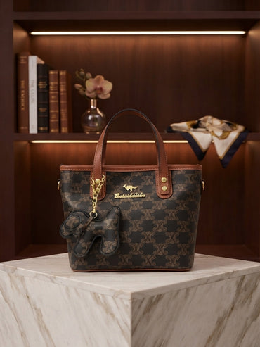 Dark monogram tote bag with tan trim, top handles, hanging animal charm and clasp
