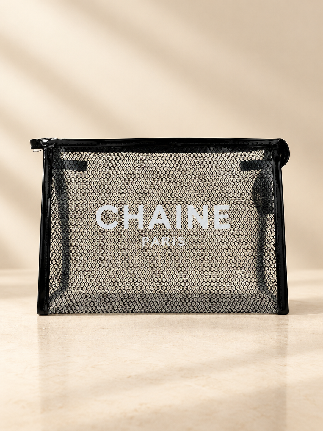 Black zip-top mesh cosmetic pouch with CHAINE Paris logo, transparent front