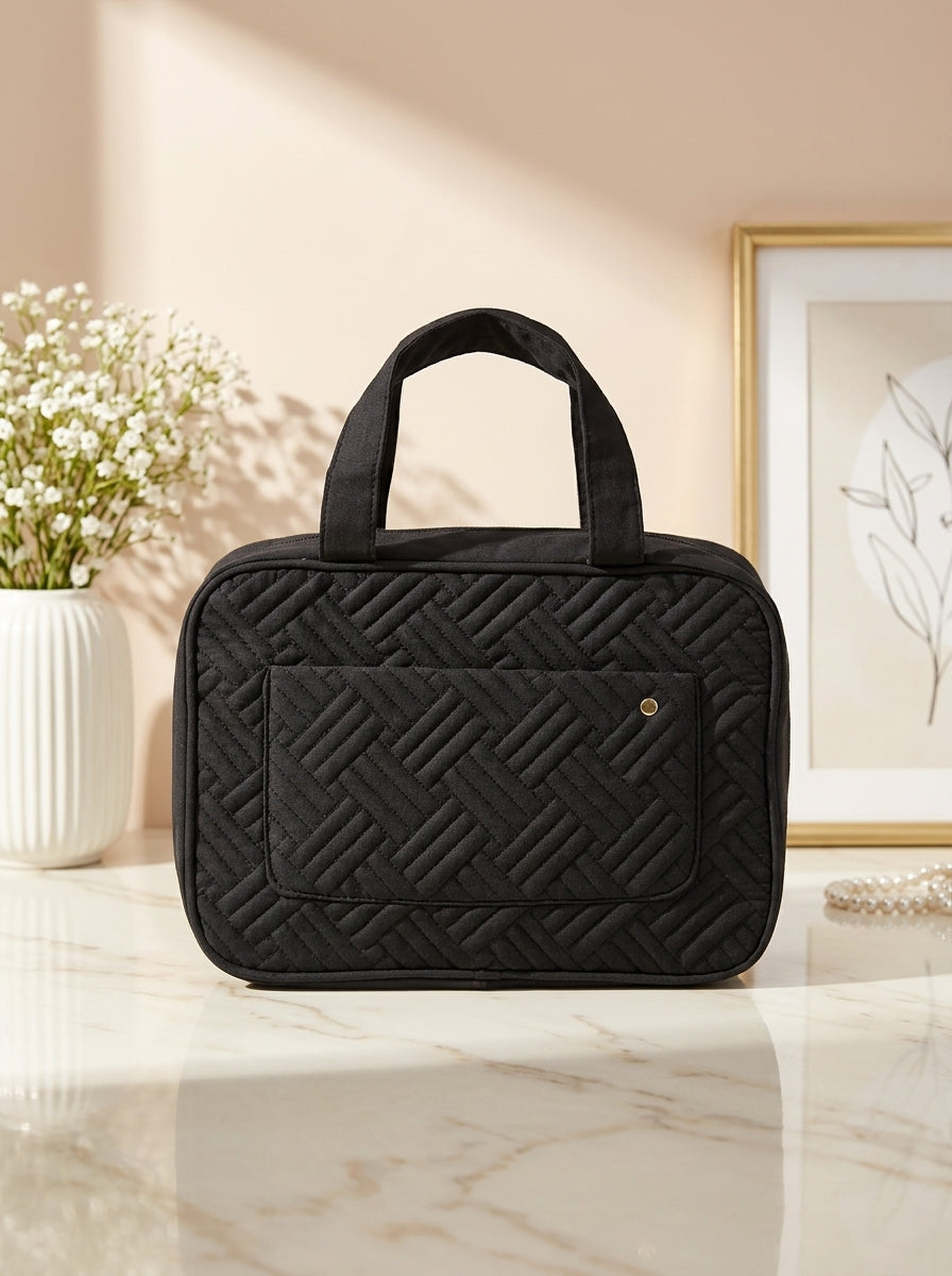 Black quilted hanging toiletry organizer bag with top handle and front zip pocket