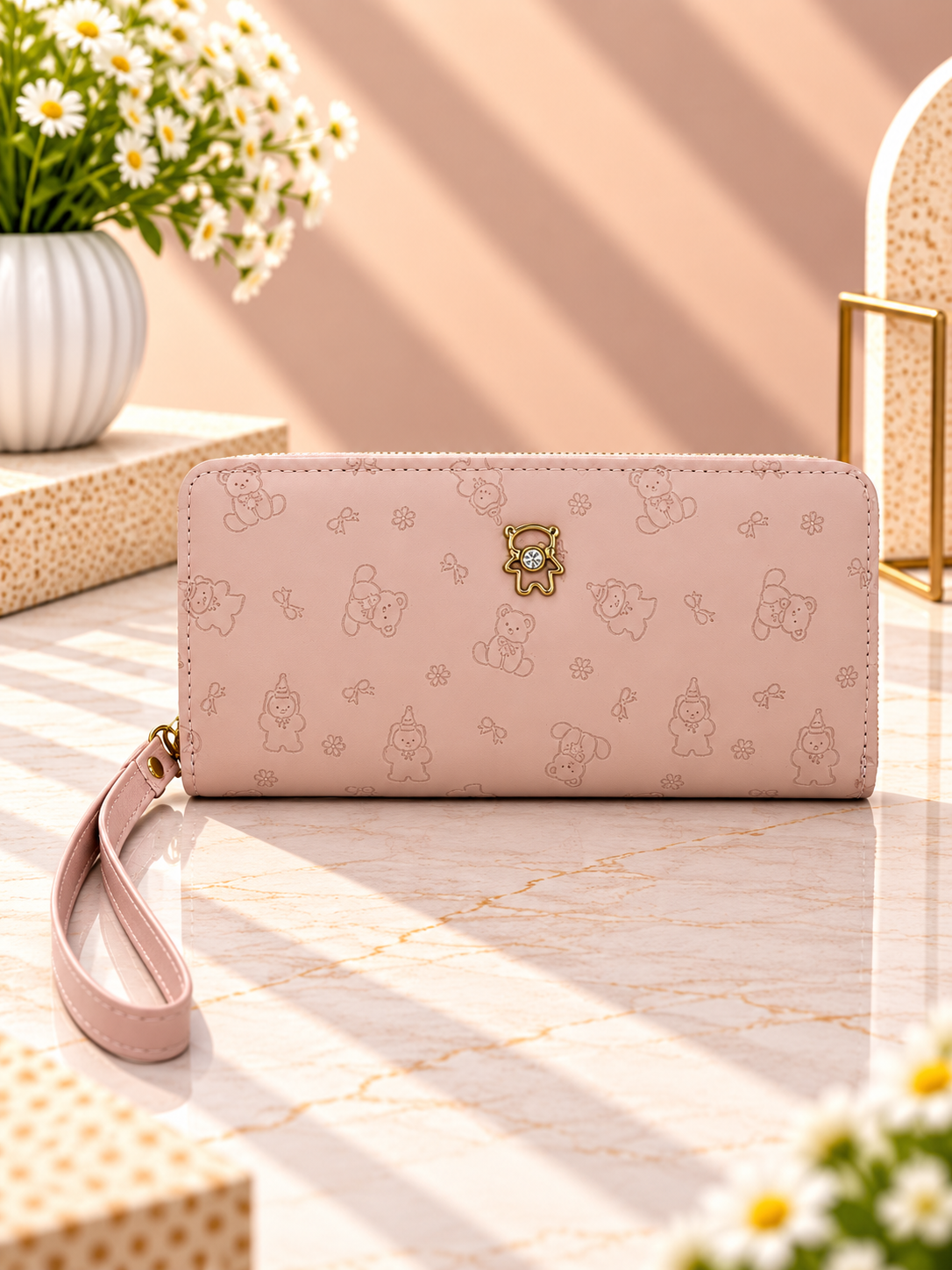Pink zip-around wristlet wallet with debossed character pattern and wrist strap