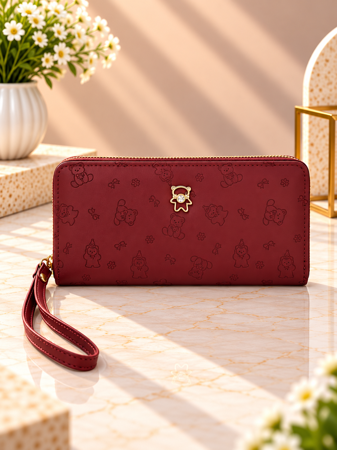 Maroon zip-around wristlet wallet with debossed character pattern and wrist strap