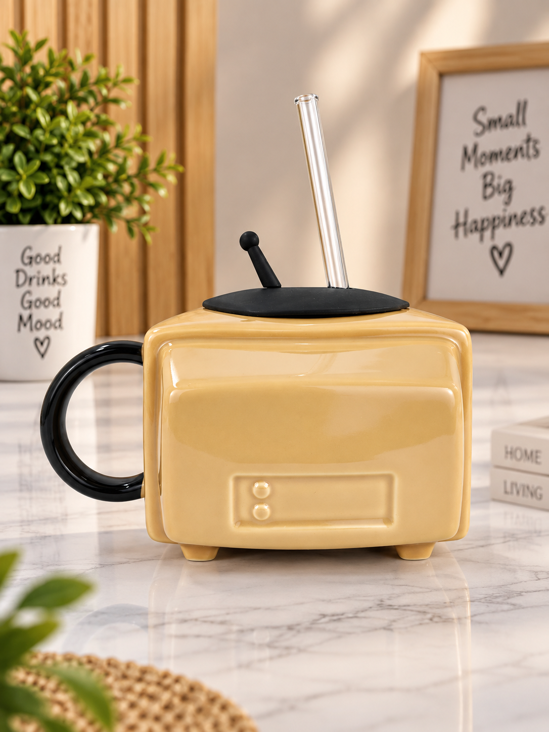 Yellow ceramic TV-style mug with black handle and two straws on lid