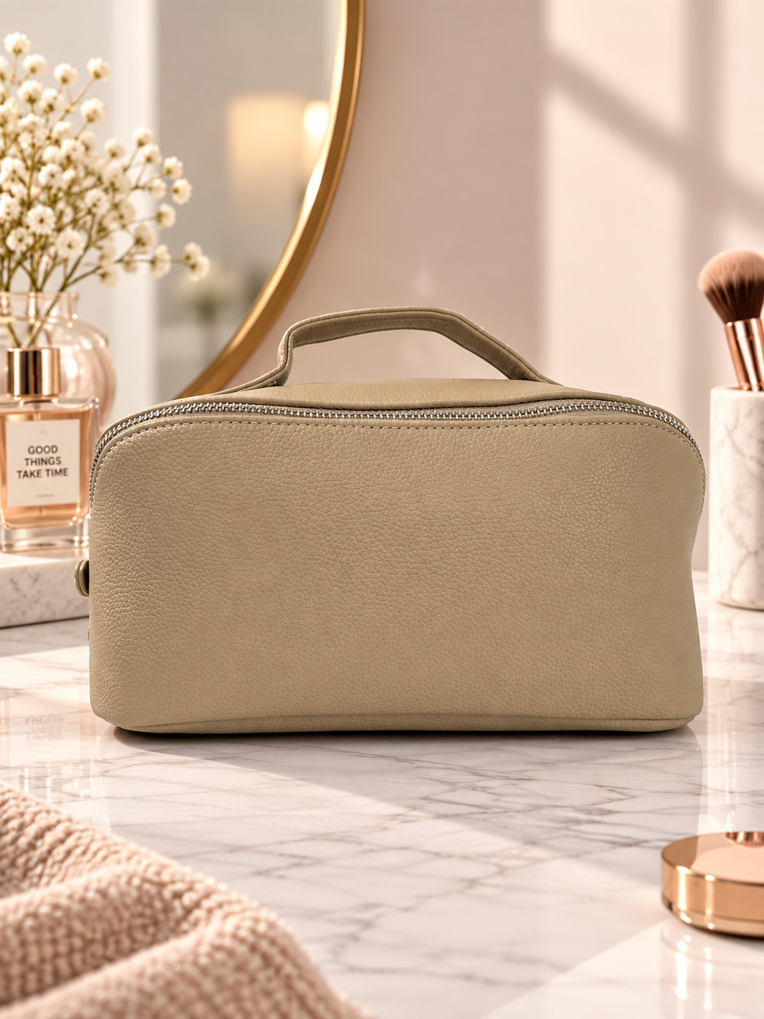 Beige pebble-textured toiletry pouch with top handle and zippered opening.
