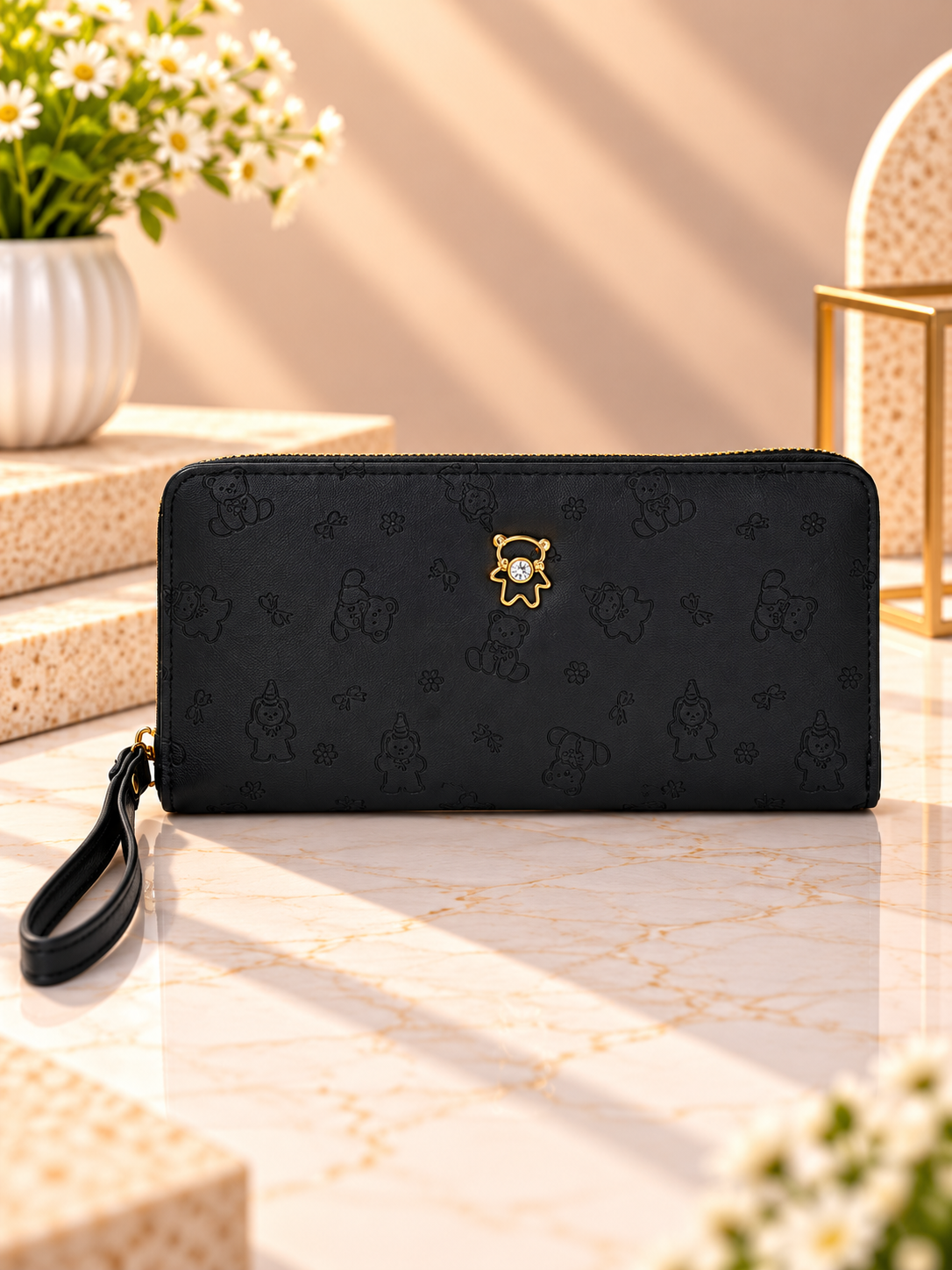 Black zip-around wristlet wallet with debossed character pattern and wrist strap
