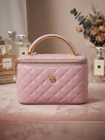 Pink quilted cosmetic case with metal handle and central gold emblem, zip top