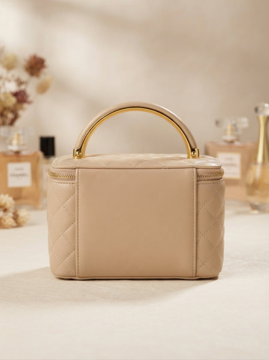 Quilted beige cosmetic case with gold metal handle, zipper, floral emblem