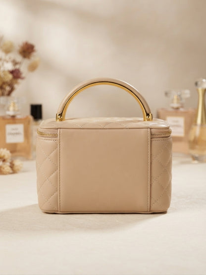 Quilted beige cosmetic case with gold metal handle, zipper, floral emblem