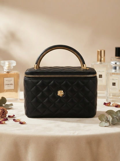 Black quilted vanity case with metal handle and central gold emblem, zip top