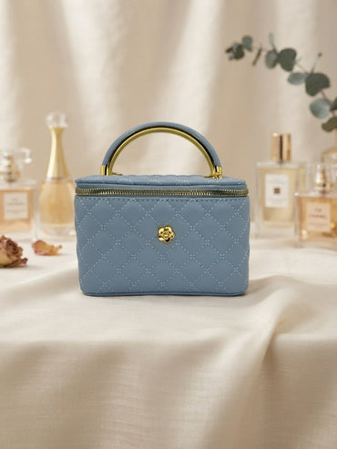 Blue quilted cosmetic case with metal handle rings and central gold emblem