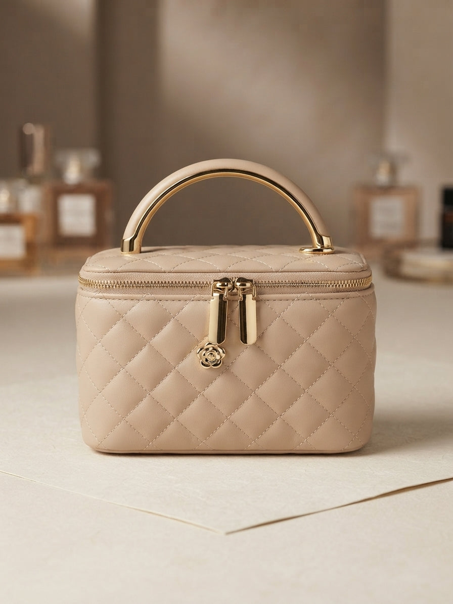 Beige quilted vanity cosmetic case with gold metal handle, front zipper and charm