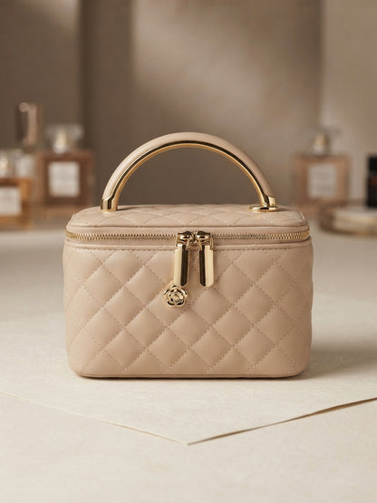 Beige quilted vanity cosmetic case with gold metal handle, front zipper and charm