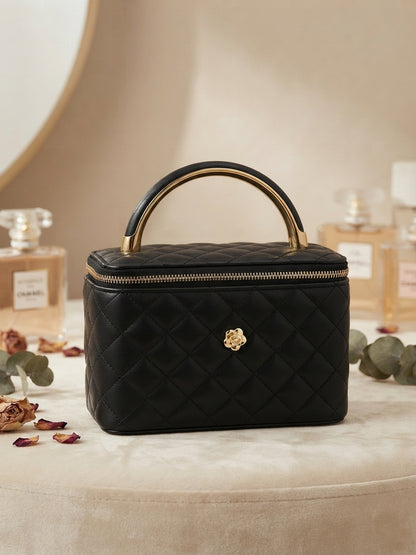 Black quilted cosmetic case with metal handle, gold emblem, and zip closure