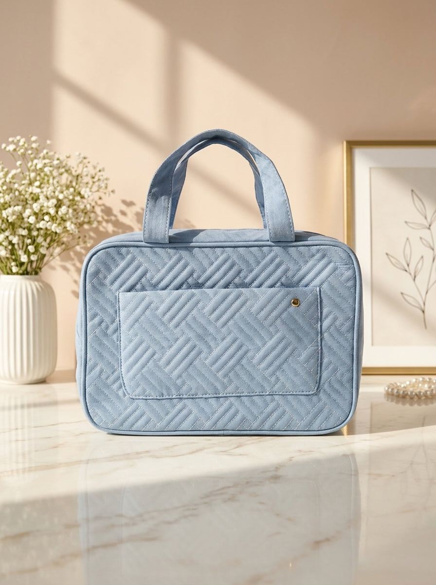 Light blue quilted hanging toiletry organizer bag with top handle and front zip pocket