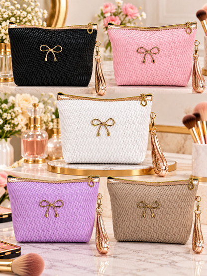 Black quilted cosmetic pouch with gold bow, zip top, and wristlet strap