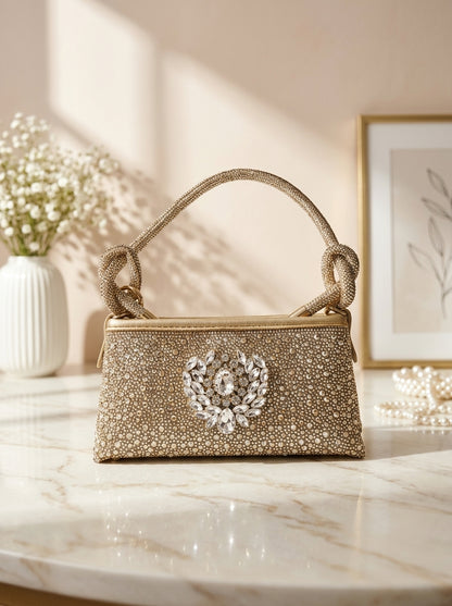 Gold glitter clutch with top knot handle and jeweled crest medallion front
