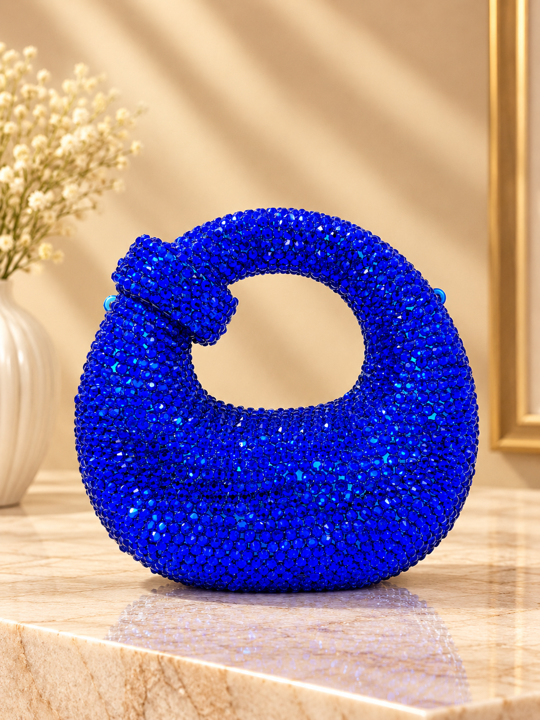Blue crystal-encrusted crescent evening bag with knotted handle and chain strap