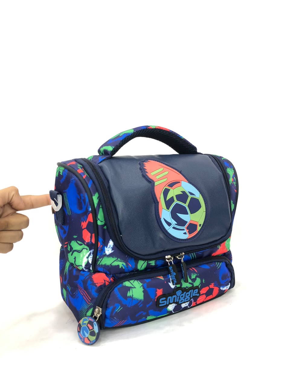 Double-decker lunchbox side view with soccer ball flap, front zip, small rolling wheels