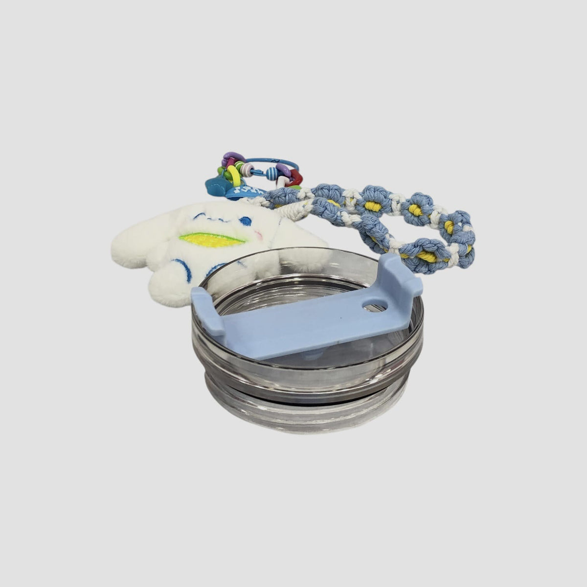 Light blue character tumbler with clear lid, metal rim, and braided plush lanyard