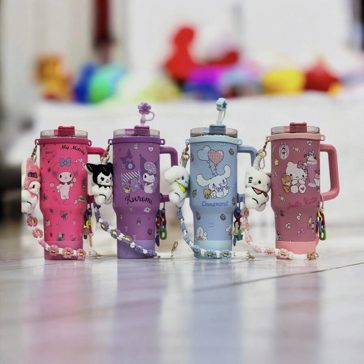 Assorted Sanrio character tumblers in pink and purple with flip lids and dangling charms