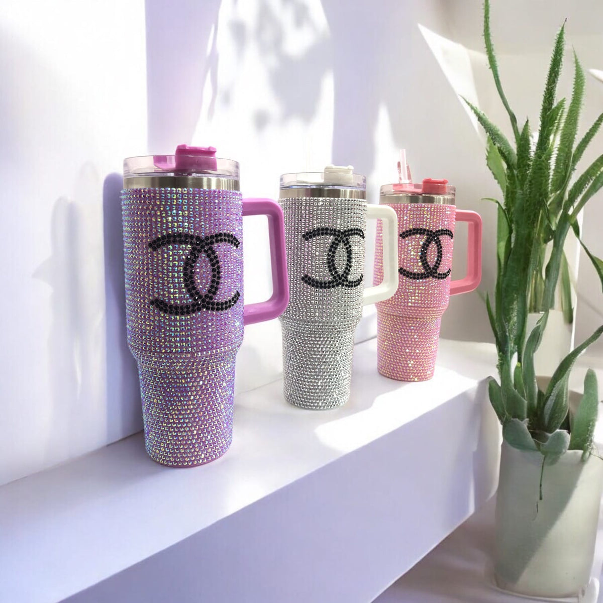 Set of rhinestone tumblers in purple, silver, and pink with black CC-style logos