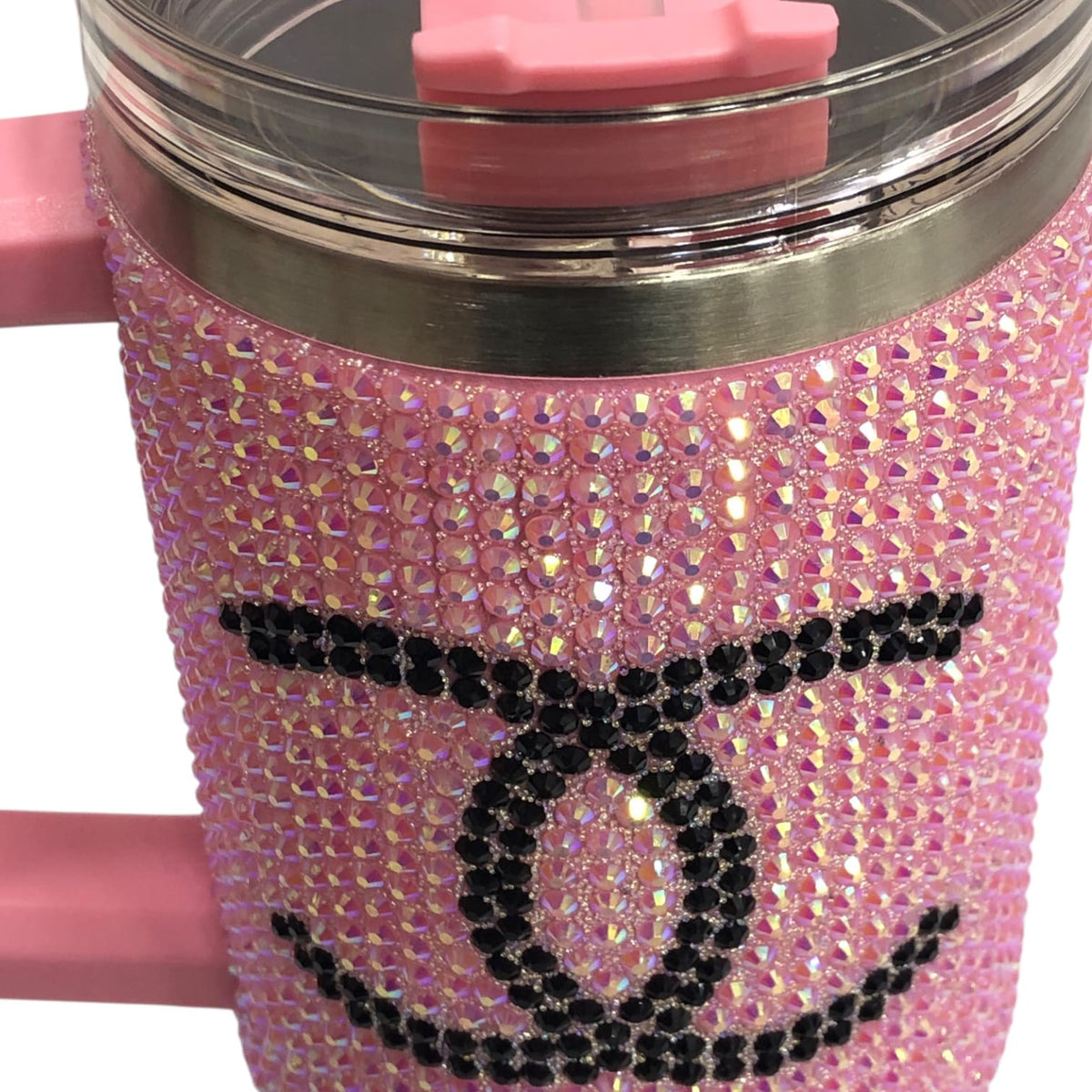 Close-up of pink rhinestone tumbler with black CC-style logo across sparkly surface