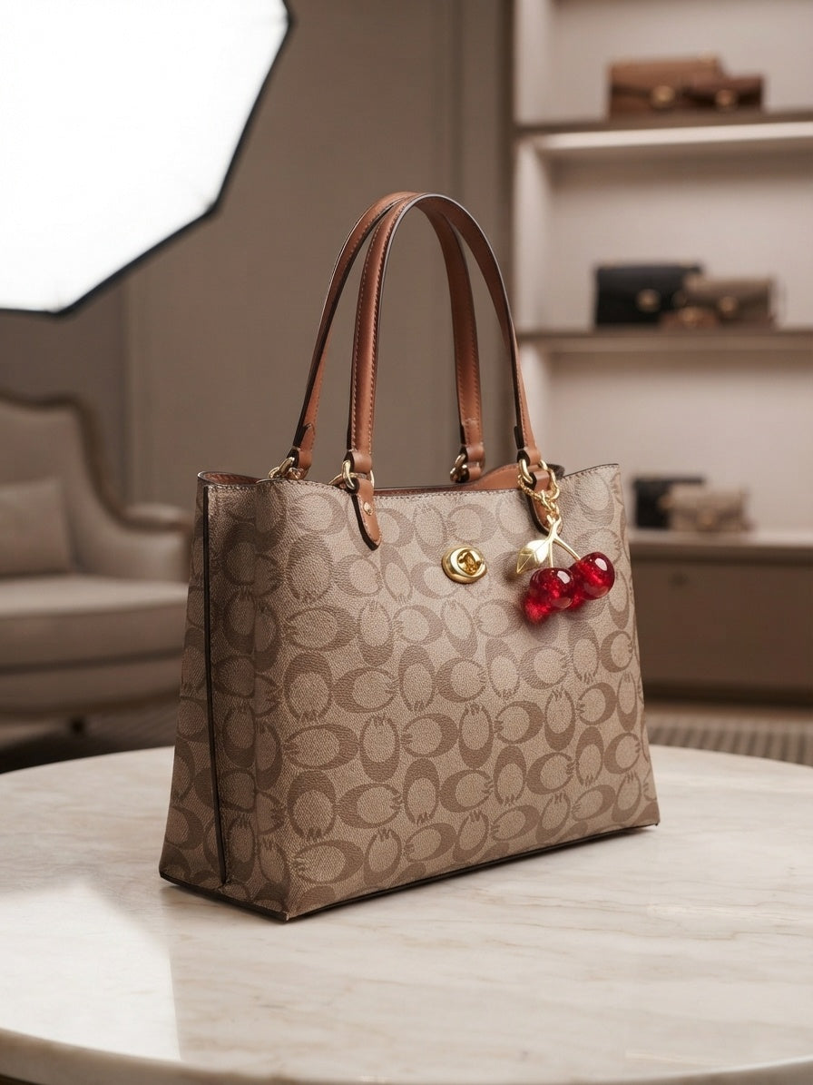 Structured beige-brown tote with repeating pattern, tan handles, red cherry charm
