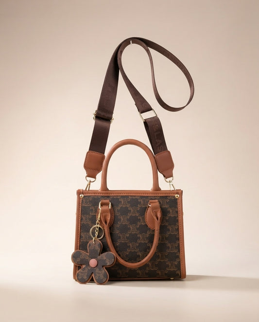Brown patterned structured tote with tan shoulder strap and hanging flower charm