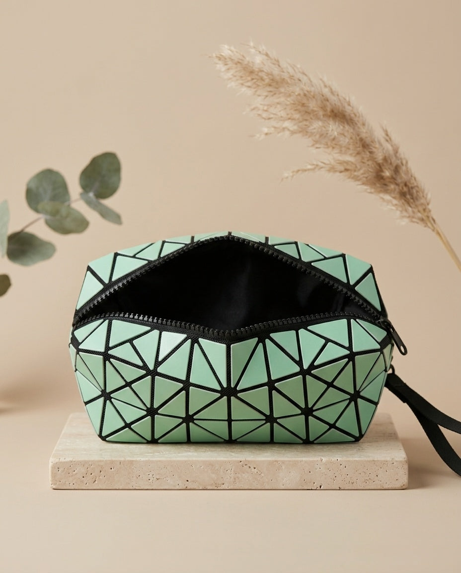 Green geometric cosmetic pouch with wristlet strap, black zip top, faceted luminous pattern