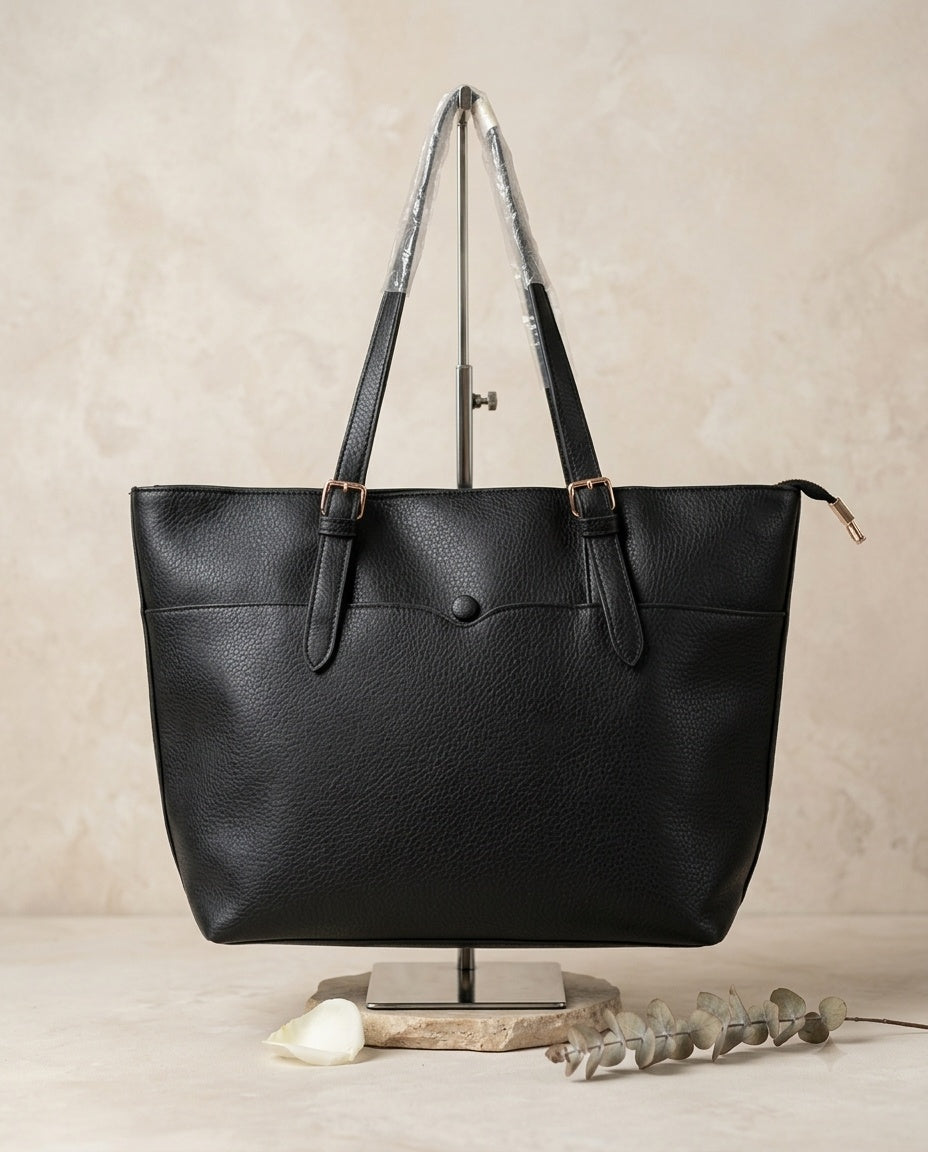 Pebbled faux leather pocket tote bag in black with buckle strap handles and front pocket