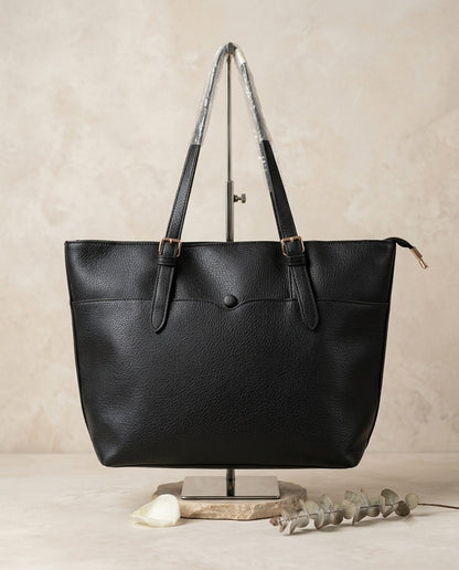 Pebbled faux leather pocket tote bag in black with buckle strap handles and front pocket