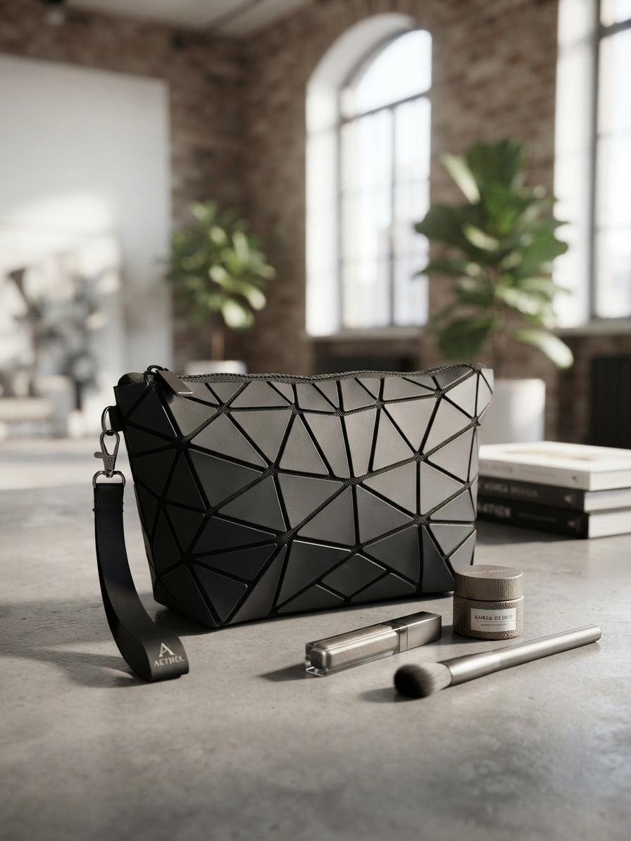 Geometric origami clutch wristlet bag in black with textured geometric pattern and wrist strap