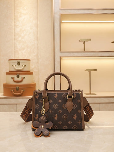 Structured brown monogram tote bag with flower charm and crossbody strap