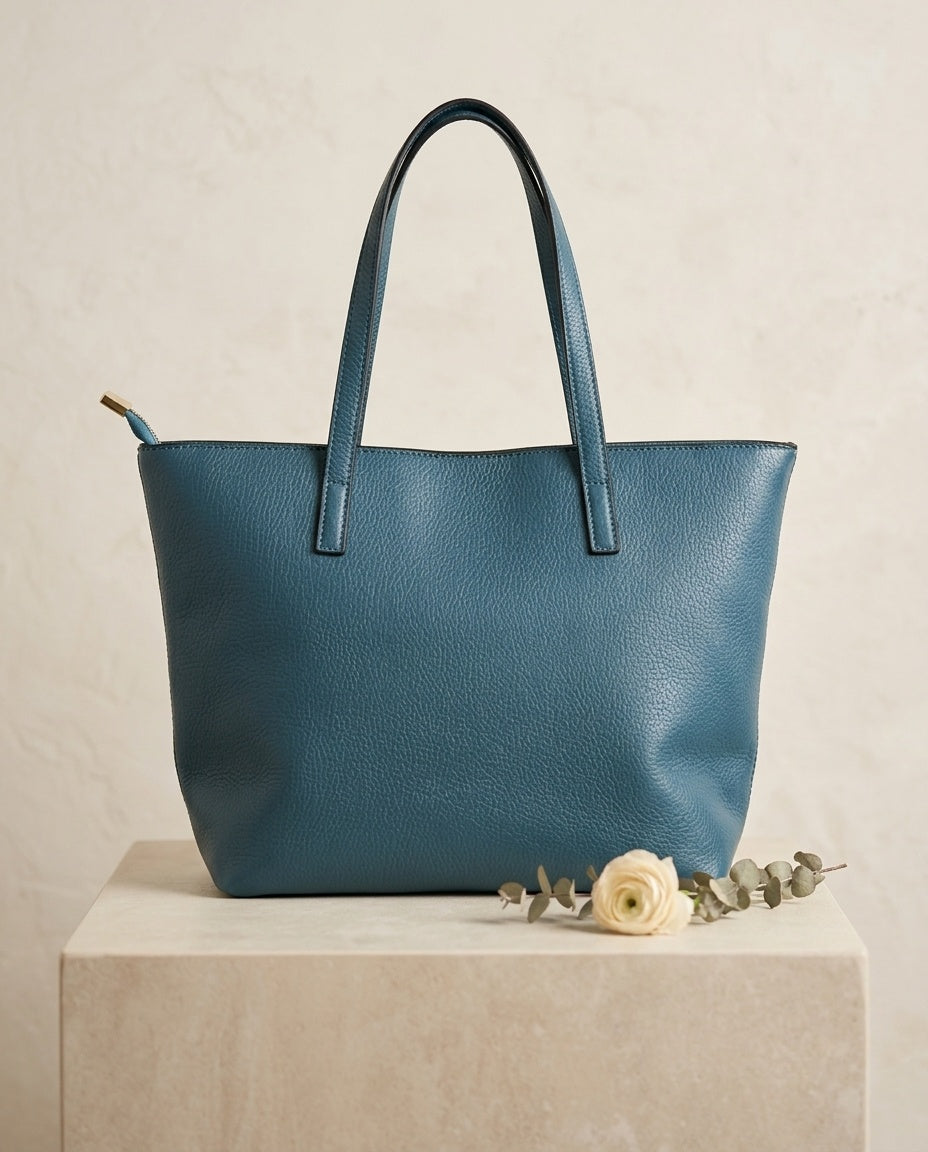 Pebbled faux leather pocket tote bag in teal with buckle strap handles and front pocket