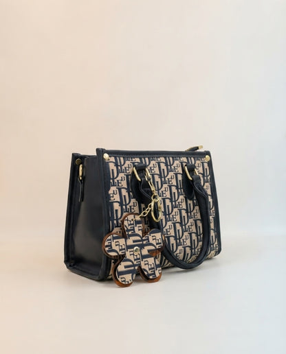 Structured tote bag with navy side panels and logo print, with dangling flower charm
