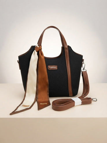 Black textured structured top-handle bag with tan scarf, tassel charm, and crossbody strap