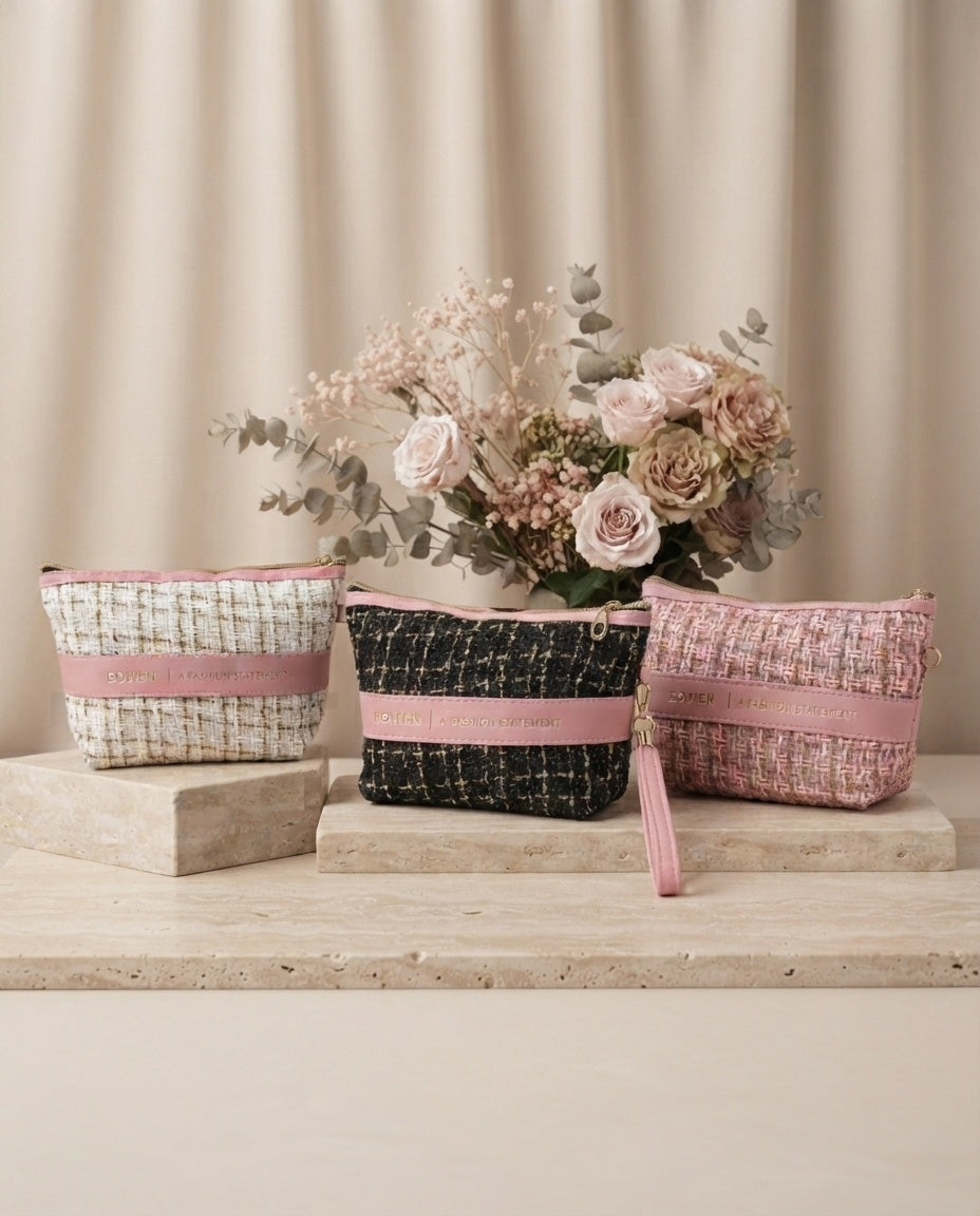 Tweed cosmetic pouch set with wristlet straps in pink, black, and beige, on display