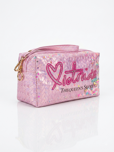 Iridescent woven makeup pouch in pink with pink heart logo, top zipper and wrist strap