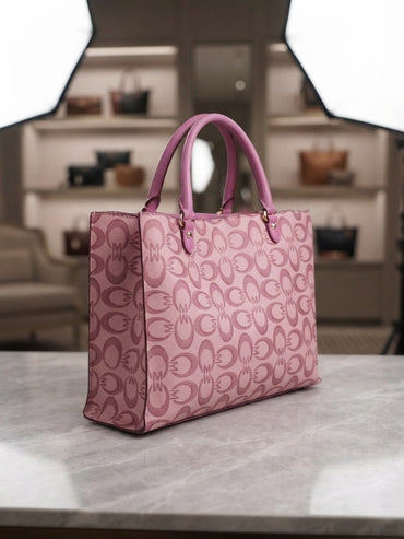 Structured pink tote with repeating pattern, pink handles, gold-tone hardware